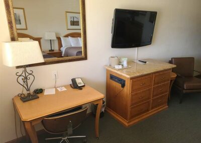 interior photo of double room with desk, mirror, dresser and flat-screen TV